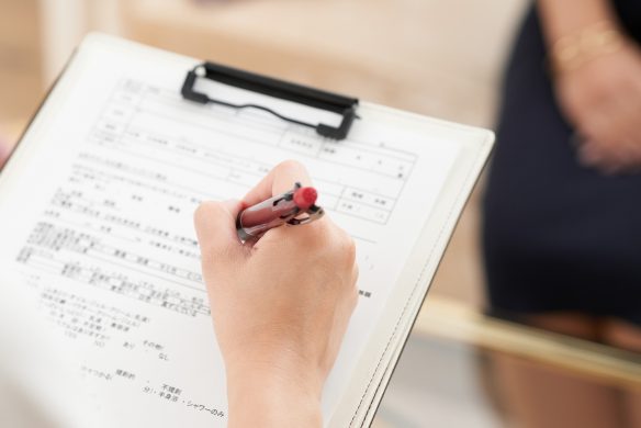 アンケート用紙にペンで回答している手元